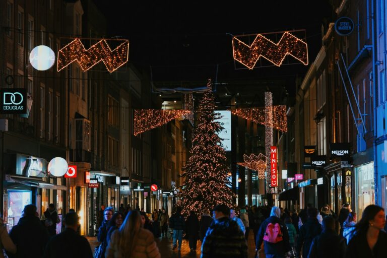 People walking down a street decorated for christmas.